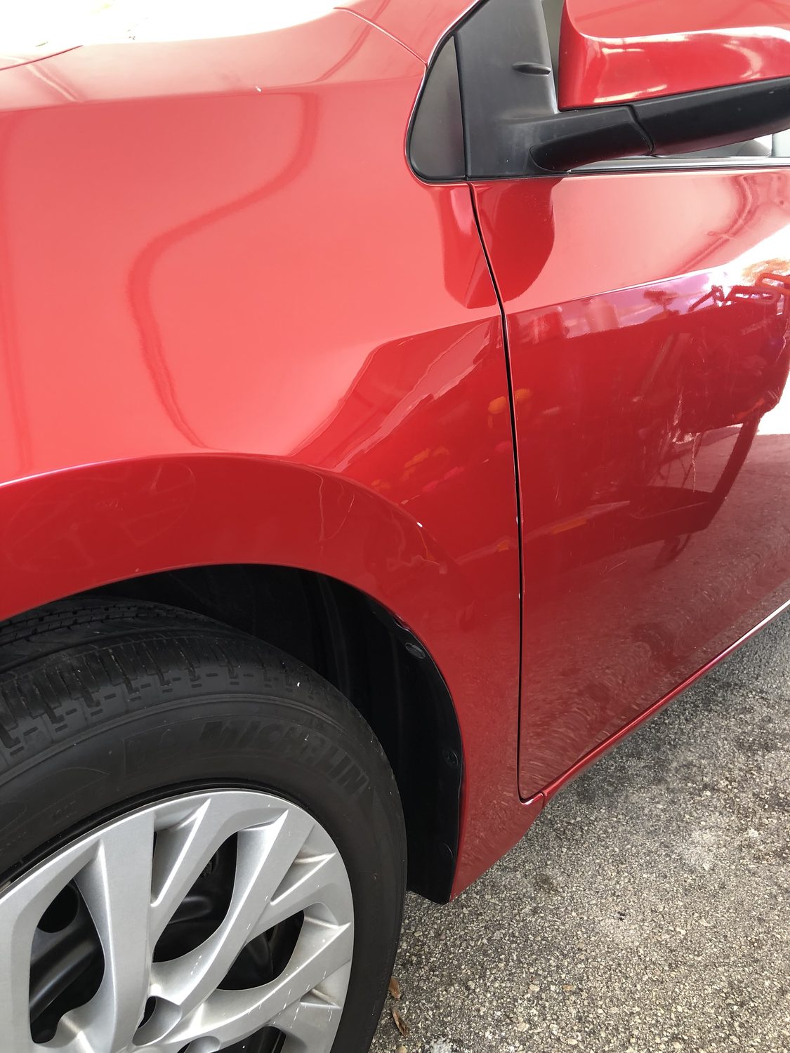 Red fender after paintless dent repair — smooth, factory paint intact, Miami