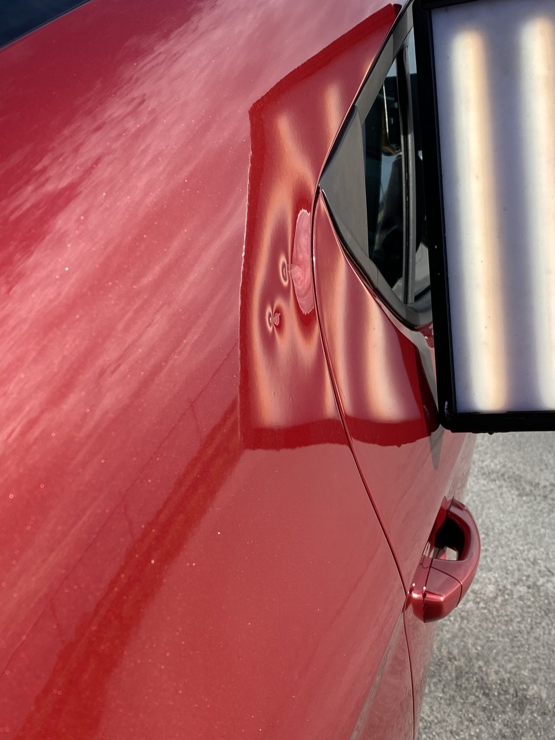 Dent on a maroon panel before paintless dent repair, Miami