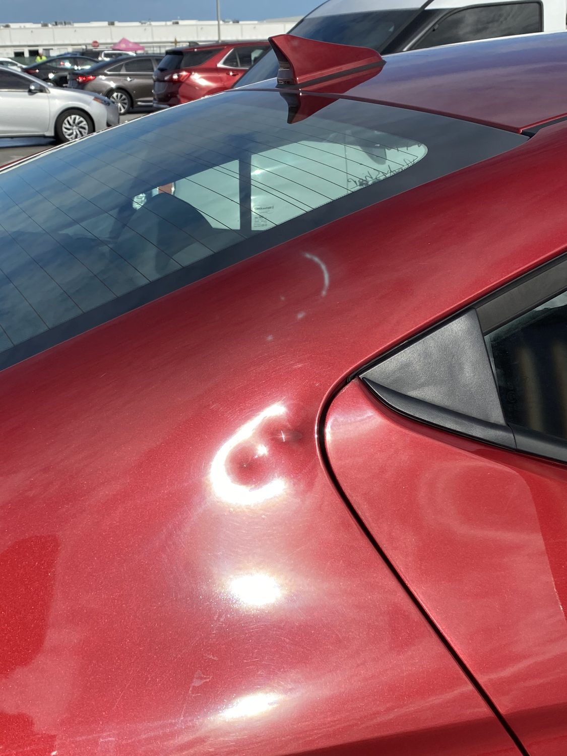 Marked dent on a maroon panel before paintless dent repair, Miami