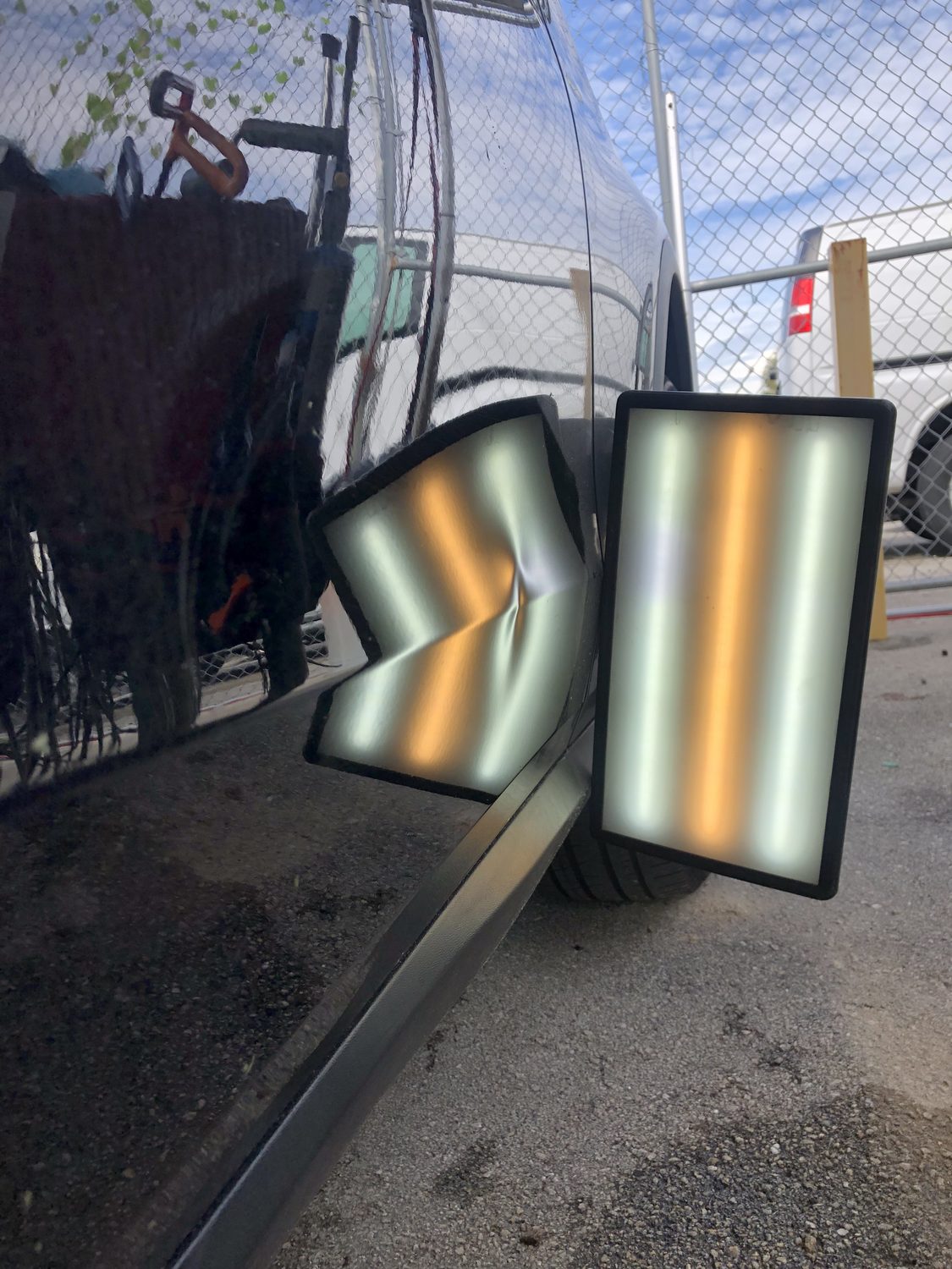 Dent on a black panel shown under a PDR reflection board, Miami