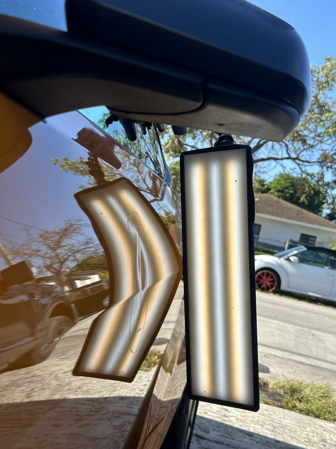 Dent on a bronze panel shown under a PDR reflection board, Miami