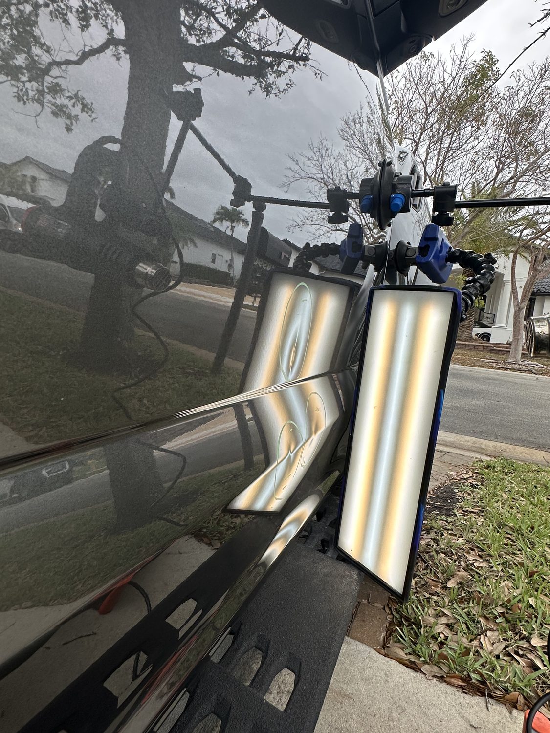 Multiple dents on a hood under a PDR reflection board, Miami