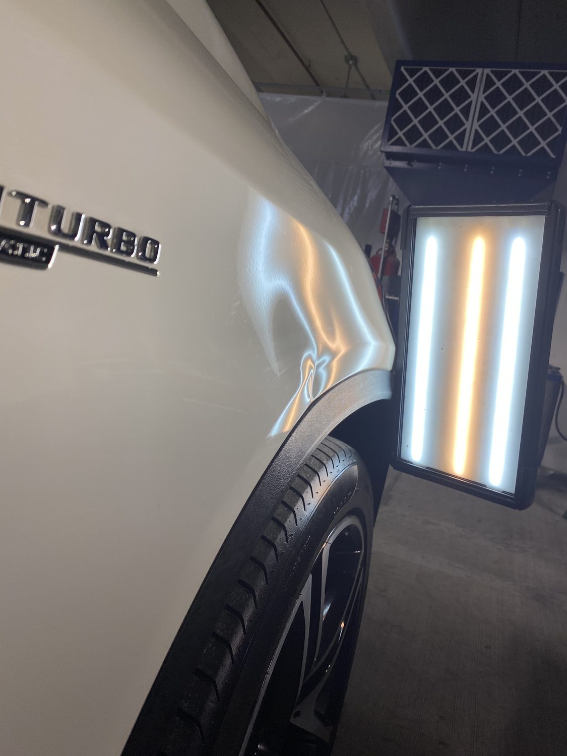 Dent on a white Mercedes AMG panel before paintless dent repair, Miami