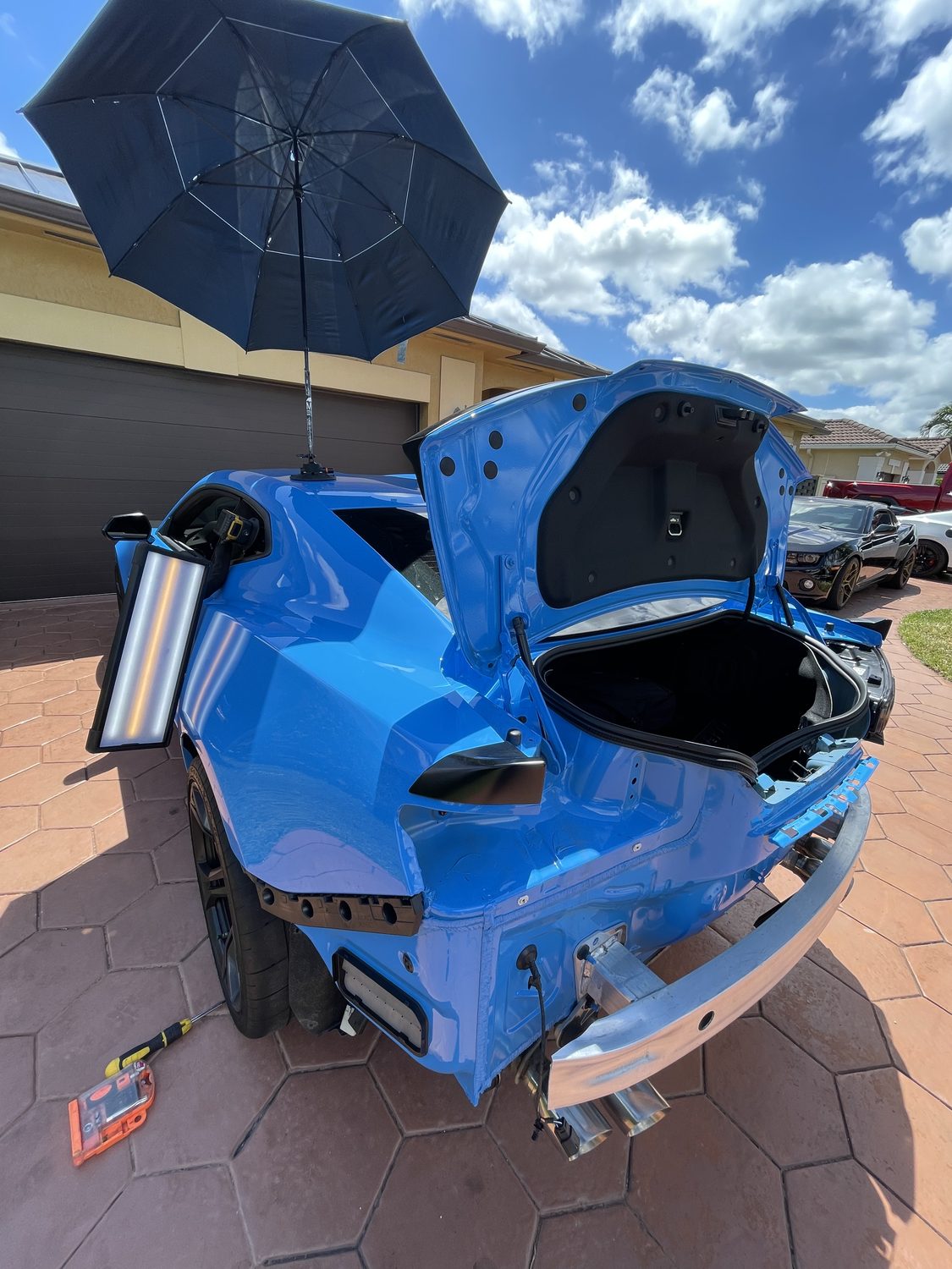 Blue sports car body panels during a restoration and dent repair, Miami