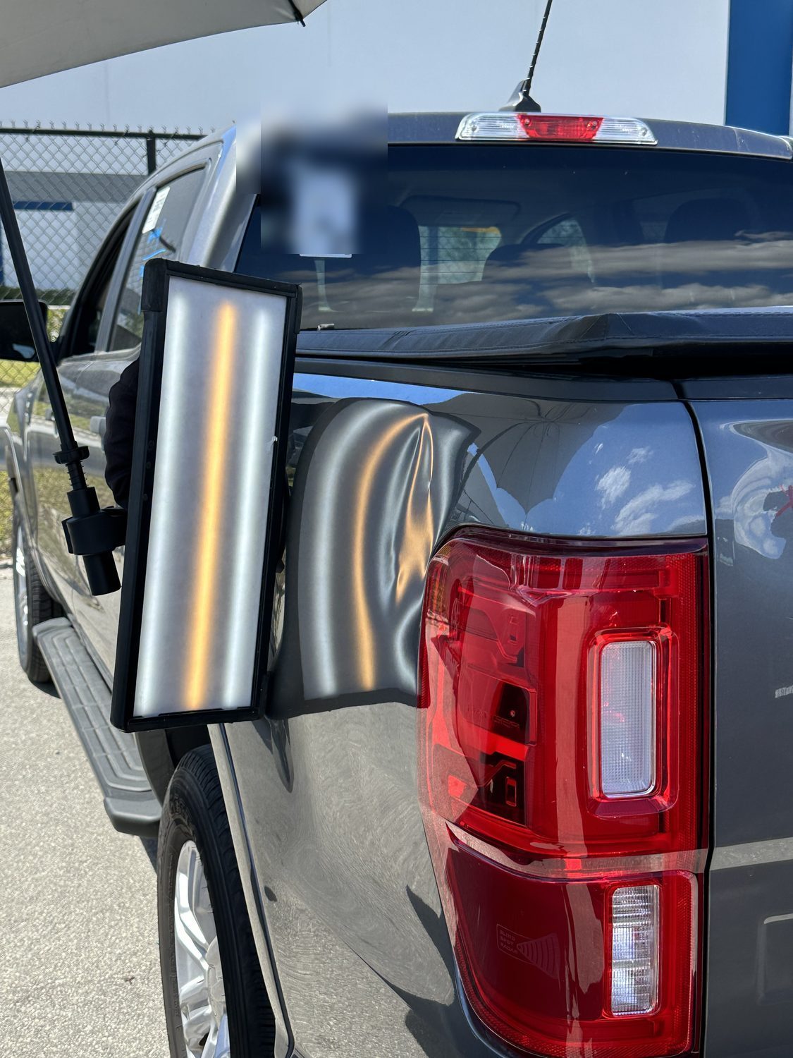 Dent on a Ford Ranger tailgate panel before paintless dent repair, Miami