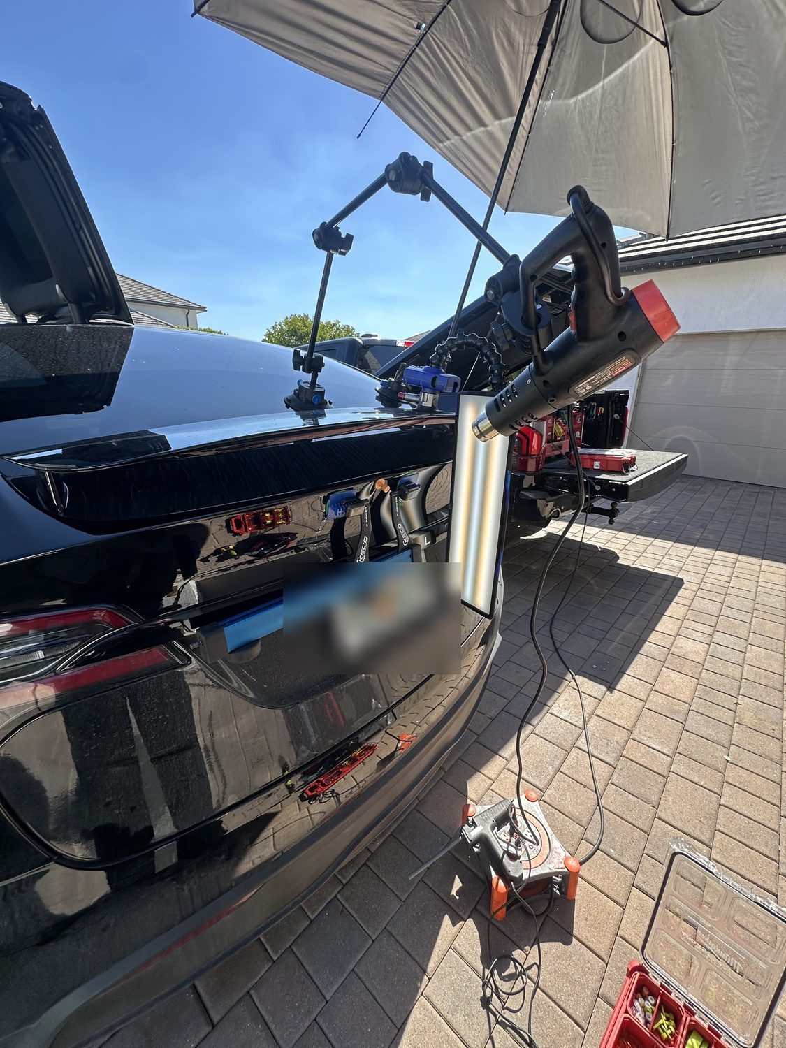 Paintless dent repair on a Tesla aluminum panel under a reflection board, Miami